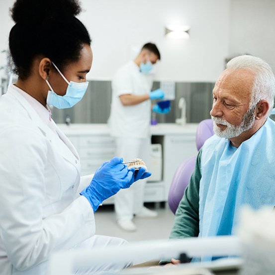 A dentist showing dentures to an older man