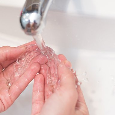 Patient rinsing off clear aligners in sink