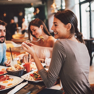 Woman smiling while eating lunch with friends at restaurant