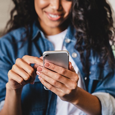 Smiling woman using phone to call dentist