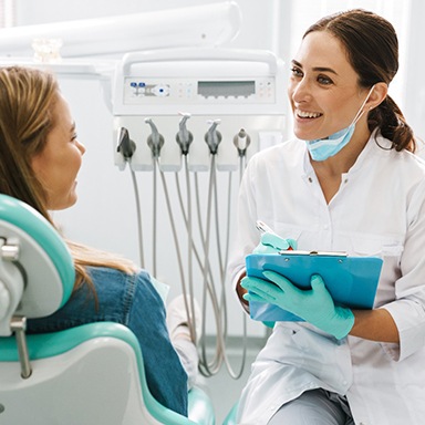 Dentist smiling while taking notes on clipboard