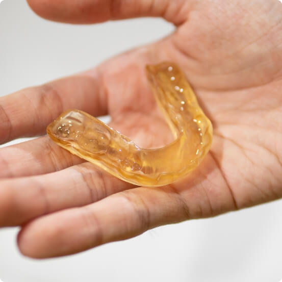 Hand holding a custom nightguard for bruxism