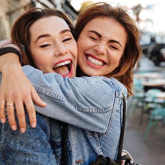 Two girls smiling while hugging outside restaurant